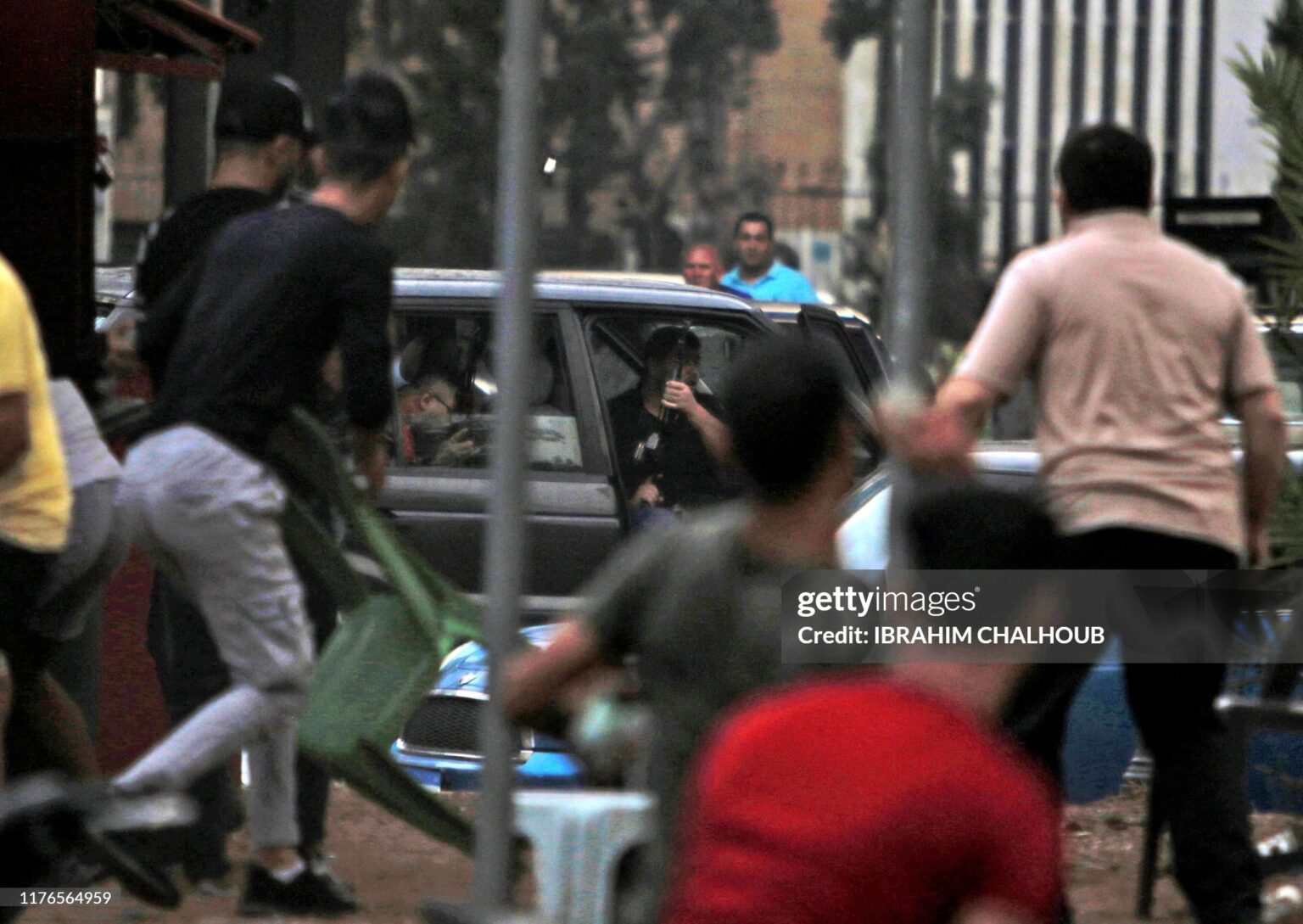 A bodyguard of former Lebanese Member of Parliament Mosbah Ahdab uses an assault rifle to fire shots in the air from his car while surrounded by demonstrators amidst ongoing protests against dire economic conditions in the northern coastal city of Tripoli on October 18, 2019. - Public anger has simmered since parliament passed an austerity budget in July to help trim a ballooning deficit and flared on October 17 over new plans to tax calls on messaging applications such as WhatsApp, forcing the government to axe the unpopular proposal. (Photo by Ibrahim CHALHOUB / AFP) (Photo by IBRAHIM CHALHOUB/AFP via Getty Images)