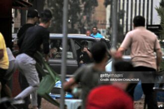 A bodyguard of former Lebanese Member of Parliament Mosbah Ahdab uses an assault rifle to fire shots in the air from his car while surrounded by demonstrators amidst ongoing protests against dire economic conditions in the northern coastal city of Tripoli on October 18, 2019. - Public anger has simmered since parliament passed an austerity budget in July to help trim a ballooning deficit and flared on October 17 over new plans to tax calls on messaging applications such as WhatsApp, forcing the government to axe the unpopular proposal. (Photo by Ibrahim CHALHOUB / AFP) (Photo by IBRAHIM CHALHOUB/AFP via Getty Images)
