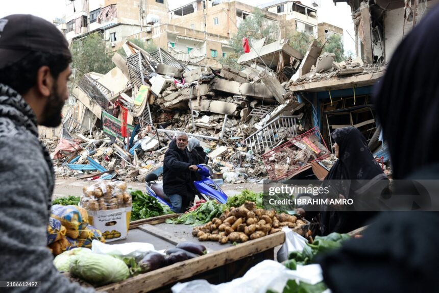 TOPSHOT - Residents buy vegetables from an ambulant vendor stationed amid the destruction in the neighbourhood of Shiyah in Beirut's southern suburbs on November 28, 2024, a day after a ceasefire between Israel and Hezbollah took effect. Since the ceasefire took effect on November 27, tens of thousands of Lebanese who fled their homes headed back to their towns, neighbourhoods and villages, only to find scenes of devastation. (Photo by IBRAHIM AMRO / AFP) (Photo by IBRAHIM AMRO/AFP via Getty Images)