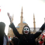 TOPSHOT - A Lebanese demonstrator, her face painted as DC comic book and film character "The Joker", takes part in a protest in the capital Beirut's downtown district's Martyr's Square on October 19, 2019. - Tens of thousands of Lebanese people took to the streets today for a third day of protests against tax increases and alleged official corruption despite several arrests by security forces. (Photo by Patrick BAZ / AFP) (Photo by PATRICK BAZ/AFP via Getty Images)